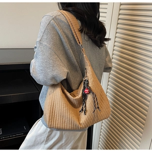 Détail du sac hobo matelassé marron clair avec coutures verticales et breloque corde