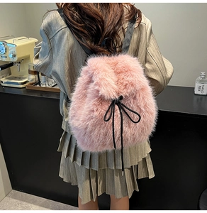 Detail view of pink plush backpack with drawstring closure worn by model in a cafe setting