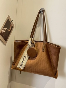 Brown vintage suede tote bag with geometric texture and decorative strap on a wall hook