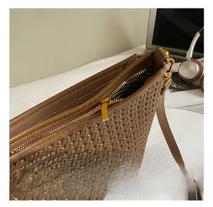Close-up of brown woven texture bag with gold hardware and striped inner lining