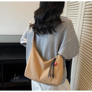 Détail du sac hobo en velours côtelé marron clair avec rayures et breloque en nœud