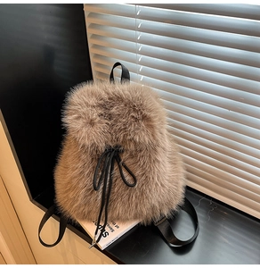 Close-up of light brown plush backpack with black straps and drawstring closure