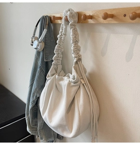 Nahaufnahme cremefarbene Cord-Schultertasche mit gerüschtem Riemen und Tunnelzug