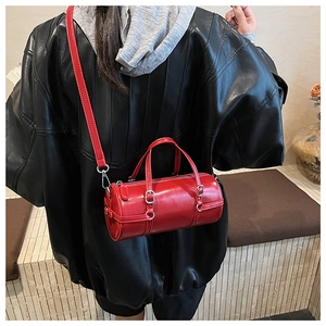 Detail of red cylindrical leather crossbody bag styled with a black leather jacket