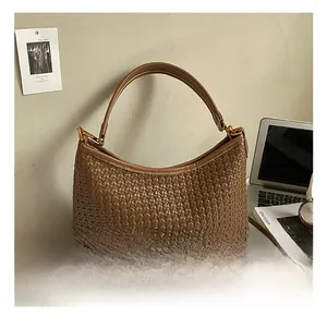 Close-up of brown woven shoulder bag with golden metallic buckles and round handle
