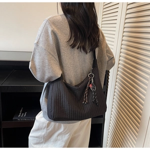 Détail du sac cabas matelassé noir avec coutures verticales et breloque en corde colorée
