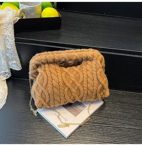 Detail of chunky knit brown shoulder bag with cable pattern and gold metal chain strap