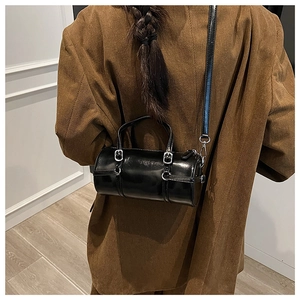Detailed back view of a black glossy cylinder bag styled with a brown corduroy jacket