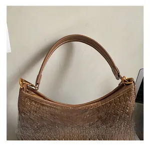 Detail showing brown woven leather texture and golden metal hardware on the shoulder bag