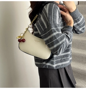Detail of cream hobo bag showing pebbled leather texture and cherry charm accessory