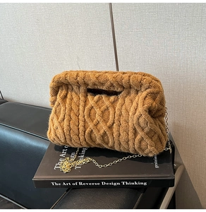 Close-up of caramel brown quilted knit clutch bag with elegant gold metal chain