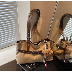 Détail du sac cabas en daim kaki avec lanières en cuir marron et pendentif ours en peluche