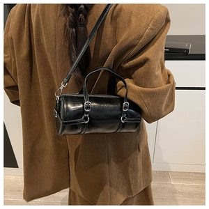 Detail view of the black cylindrical crossbody bag with silver hardware and adjustable strap