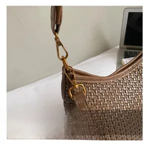 Detail of the bronze gold carabiner hook on a brown woven shoulder bag with leather texture