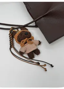 Detail of a plush bear charm on a brown tote bag with high-quality woven strap