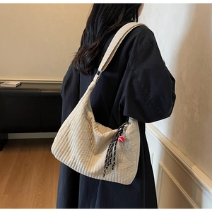Gros plan du sac fourre-tout matelassé crème avec breloque raquette de tennis
