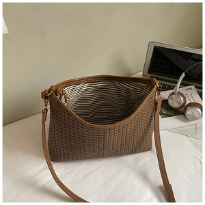 Detail view of woven brown shoulder bag showing striped interior and metal hardware
