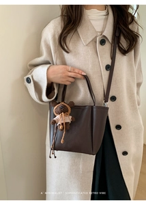 Detail of dark brown lychee leather tote bag with cute bear charm and adjustable strap