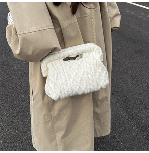 Detail of white cable knit quilted handbag featuring textured weave and gold metal chain strap