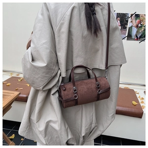 Detailed view of a brown cylinder bag in matte leather featuring silver metal hardware
