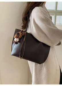 Side view of large lychee texture tote bag with cute brown bear plush pendant and long strap