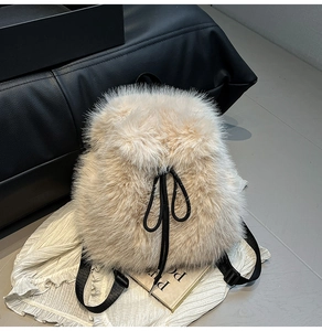 Detail of soft cream faux fur texture and black drawstring closure on the plush backpack