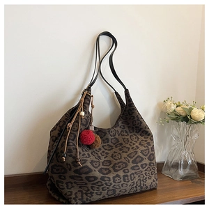Detail of leopard print hobo bag with red pompom charm and wooden beads on canvas