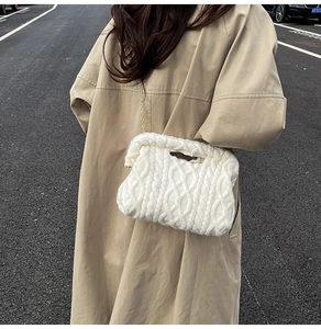 Detail of white cable knit bag with golden chain strap on a model wearing a trench coat