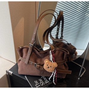 Détail du sac cabas en daim marron foncé avec boucles en cuir et breloque ourson