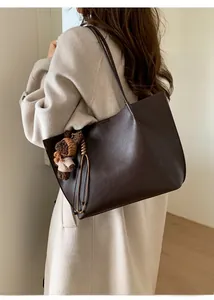 Deep brown tote bag with bear charm shown on model in a minimalist stylish outfit