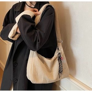 Détail du sac hobo matelassé beige avec coutures texturées et breloque raquette de tennis