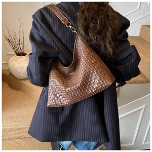 Detailed view of brown woven hobo bag with wide leather strap and gold hardware accents