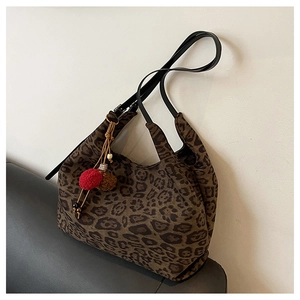 Close-up of leopard print canvas hobo bag with colorful pompom charms and wood beads