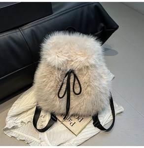 Close-up of beige faux fox fur backpack with decorative black drawstring bow detail