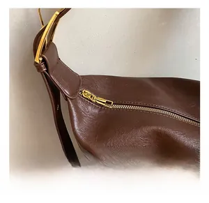 Close-up of premium brown leather texture with high-quality gold hardware and zipper detail