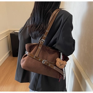 Vue détaillée du grand sac cabas en daim marron foncé avec sangles et breloque ours peluche