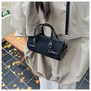 Detail of black cylindrical crossbody bag with matte finish on a trench coat model