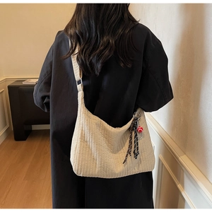 Détail du sac hobo beige avec texture plissée et breloque de tennis sportive