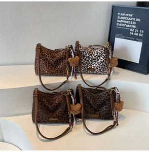 Detailed view of four leopard print tote bags with bear charms and scarves on white steps