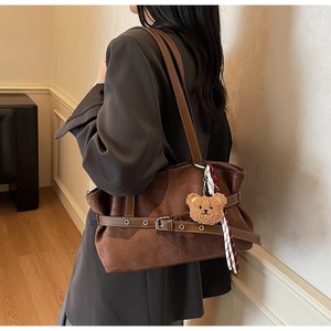 Vue détaillée du sac cabas vintage en daim marron avec sangles et breloque ours en peluche