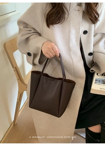 Deep brown lychee pattern leather tote bag held by a model in a minimal beige coat