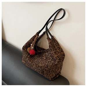 Detail of leopard print tote bag with soft texture and decorative pom-pom tassel charm