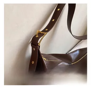 Detail of adjustable shoulder strap with vintage bronze buckle on brown leather bag