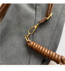 Gros plan du crochet doré et de la poignée en cuir marron sur un sac fourre-tout
