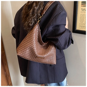 Detail of dark brown woven leather shoulder bag with gold metal hooks and smooth strap