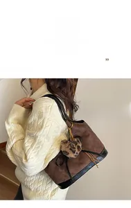 Close-up of brown quilted shoulder bag with leopard print pompom on female model