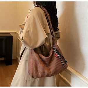 Detail view of brown quilted hobo bag with colorful tassel pendant on a stylish model