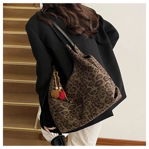 Macro detail of leopard print canvas tote bag with decorative plush pom-pom charm