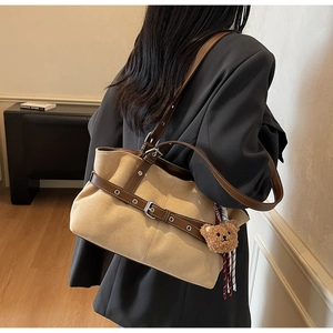 Détail du sac fourre-tout en daim kaki avec garniture en cuir marron et pendentif ours peluche