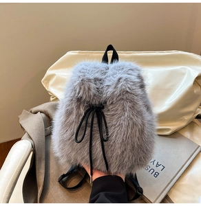 Detail of soft grey faux fur backpack with black drawstring closure and stylish webbing straps